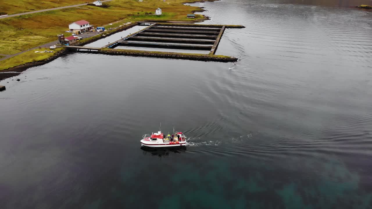 paralaje aéreo de un barco que navega hacia la costa en un pequeño puerto en un hermoso fiordo con aguas claras de las islas feroe