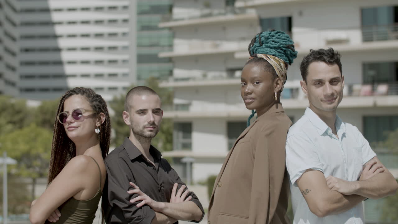 팔짱을 끼고 포즈를 취하며 등을 맞대고 서 있는 진지한 동료들