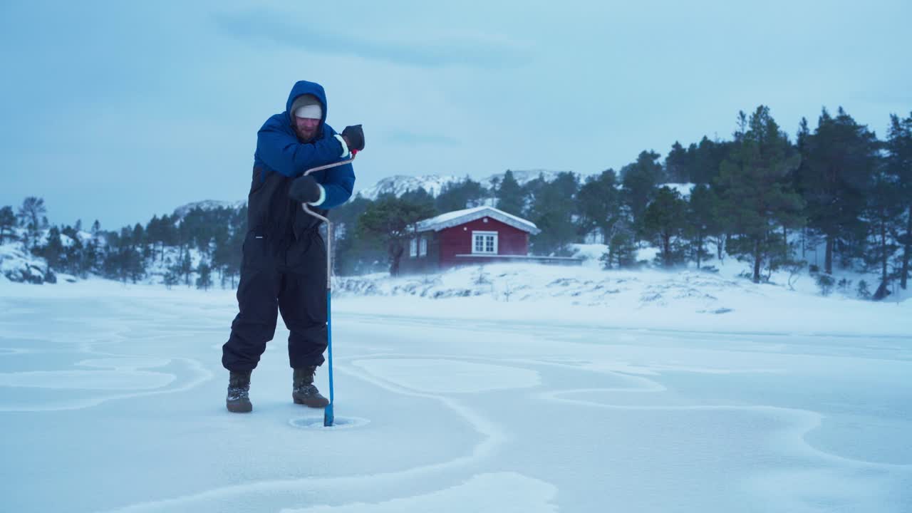 En mann lager en åpning i en frossen innsjø for isfiske i Bessaker, Trøndelag fylke, Norge – Statisk opptak