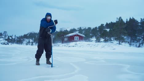 Un-Hombre-Está-Creando-Una-Abertura-En-Un-Lago-Congelado-Para-Pescar-En-El-Hielo-En-Bessaker,-Condado-De-Trondelag,-Noruega---Toma-Estática