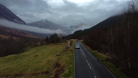 Drone-Siguiendo-El-Coche-A-Lo-Largo-De-Una-Carretera-Panorámica-En-El-Valle-De-Glen-Nevis,-Escocia