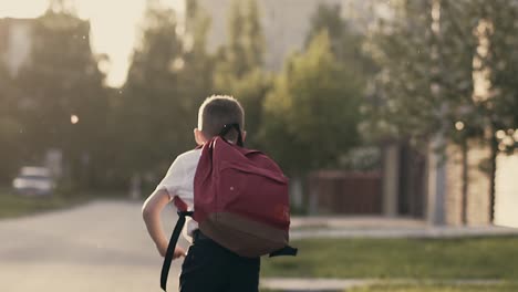 CU-Tracking-Slow-motion-Schoolboy-after-school-hours-runs-home-Behind-him-is-a-school-satchel