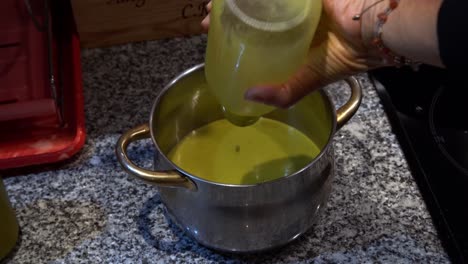 vertiendo sopa embotellada en la olla