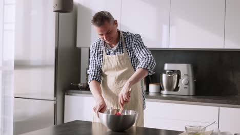 mujer besando a su esposo de pie en la mesa en la cocina mezclando ingredientes en un tazón