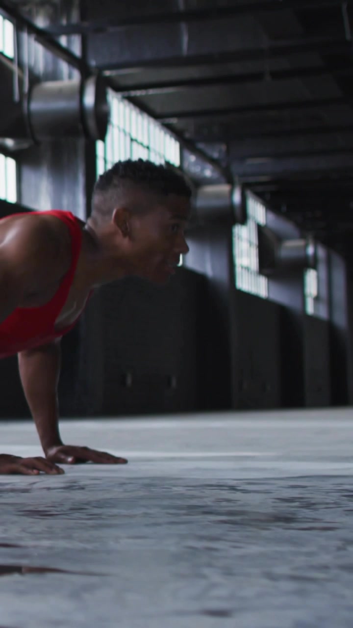 Video verticale: Uomo che mantiene una posizione bassa di flessione, fa flessioni per il fitness in palestra, con una sovrapposizione blu che traccia le ripetizioni