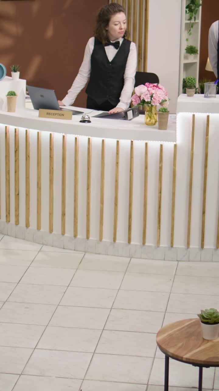 Uomini d'affari che chiedono informazioni sui servizi dell'hotel in un video verticale
