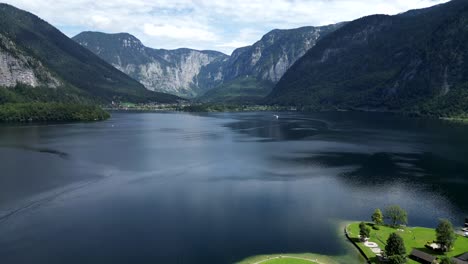 breathtaking aerial drone footage captures a serene blue lake, the majestic alps in the background, and a charming village nestled along the lakeside for stunning scenic beauty.