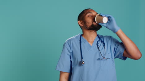 tired healthcare specialist gaining energy with cup of coffee while at work,