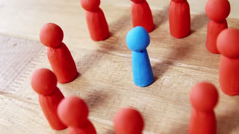 blue figurine standing between a group of red figurines