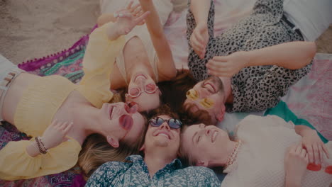 happy young friends lying on sarong at beach