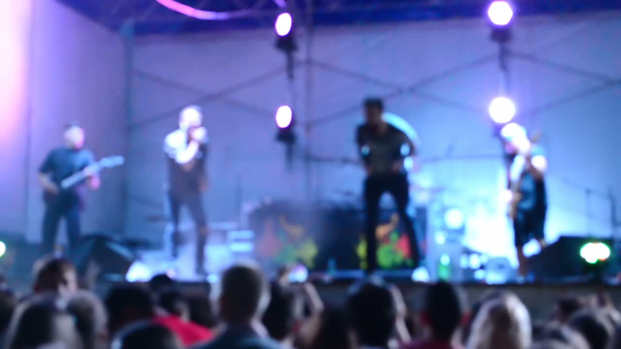 Performance de grupo de rock em um palco. Fora de foco. Filmagem noturna.