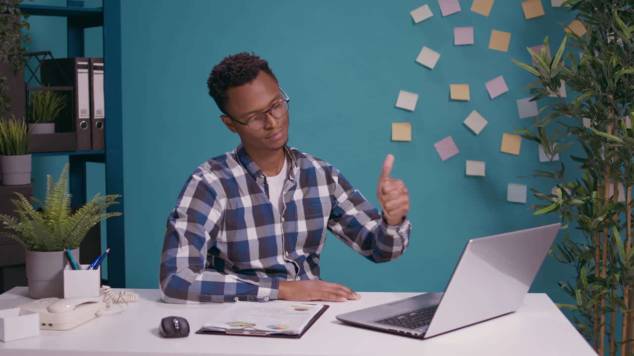 Positive employee giving thumbs up in front of laptop screen