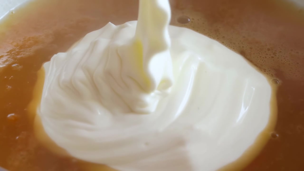 Primer plano de crema vertiéndose en una taza de café, con una crema blanca sedosa formando un remolino concéntrico sobre la rica superficie del espresso.