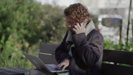 Confident-businesswoman-talking-on-smartphone-while-using-laptop