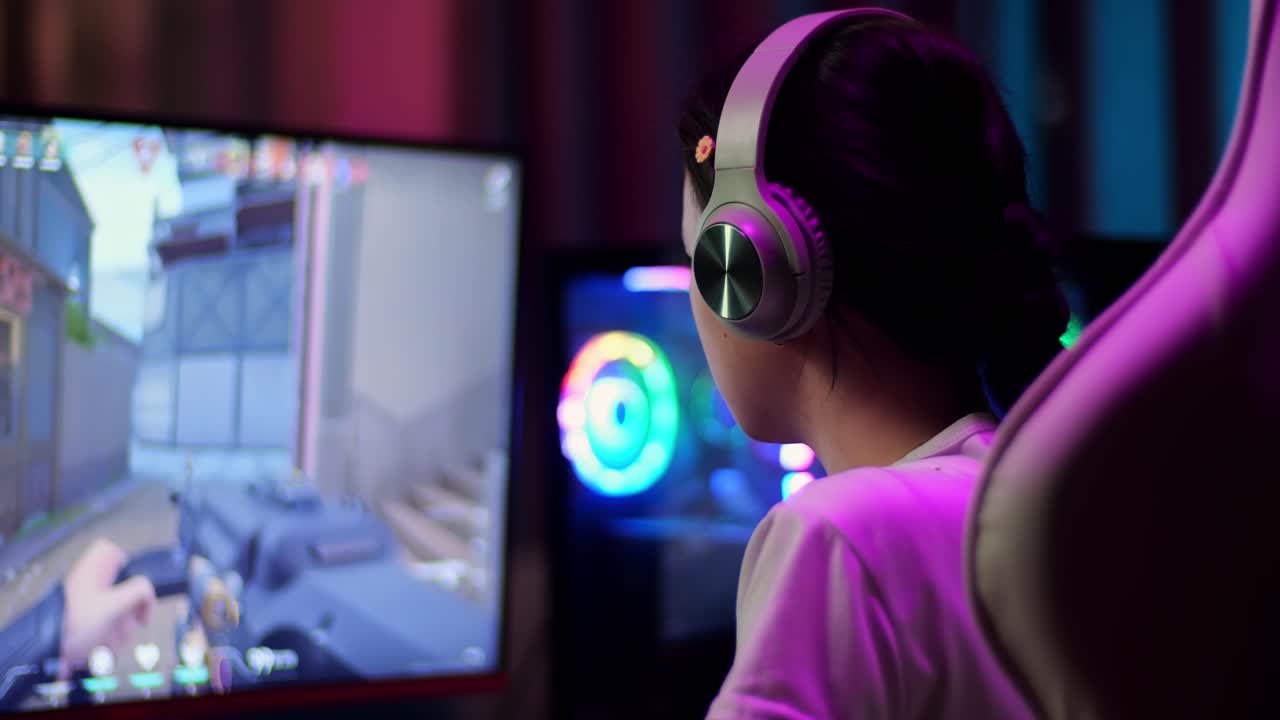 Primo piano di una giocatrice adolescente asiatica entusiasta che festeggia la vittoria mentre gioca a un videogioco sparatutto online al computer.