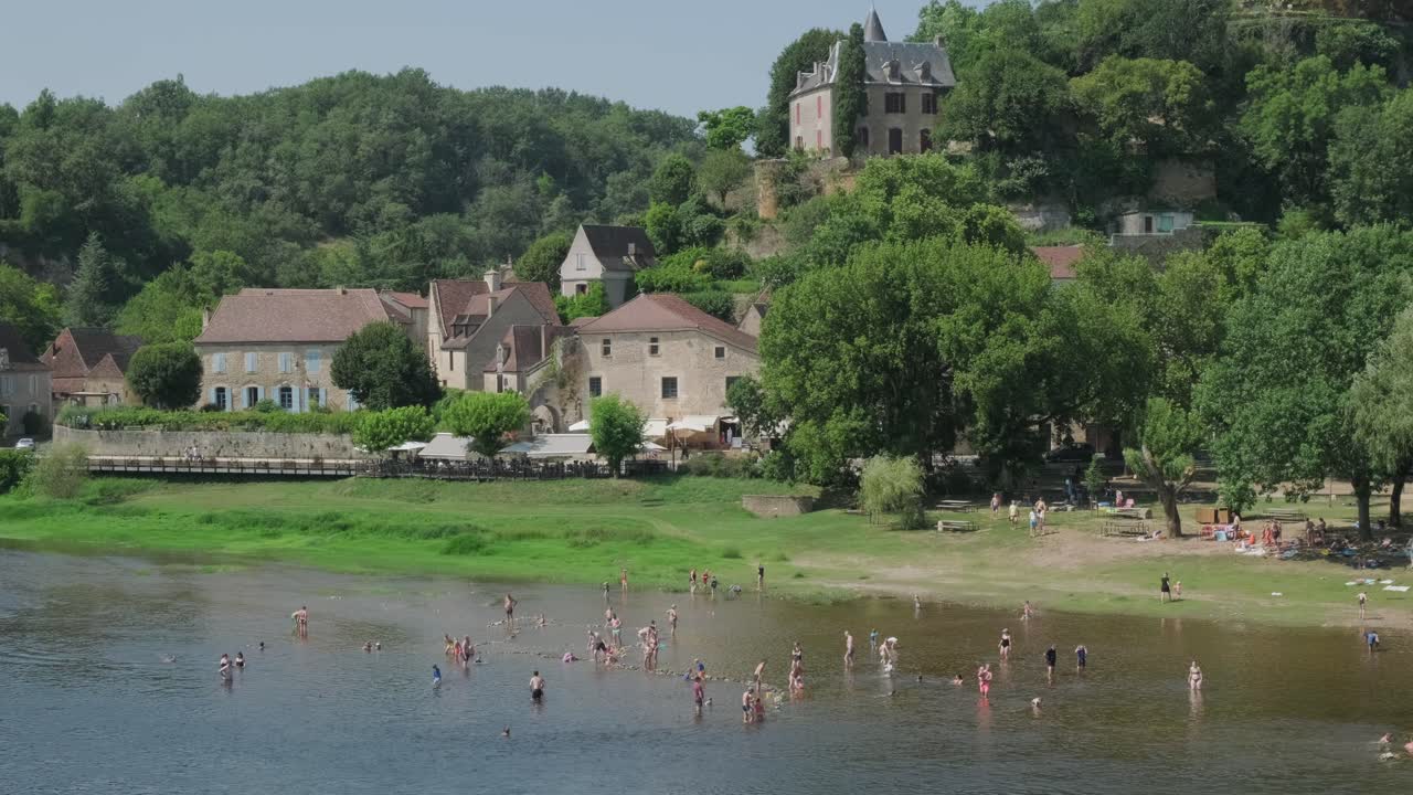 people enjoying the summer on a river in france with old houses in the background in slow motion