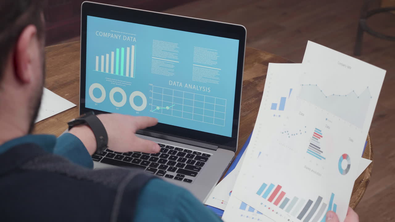 Analyzing Company Data with Laptop and Charts