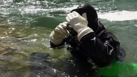 Female-technical-side-mount-scuba-diver-gears-up-in-cold-river-water