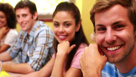 Students-sitting-in-a-line-smiling-at-camera