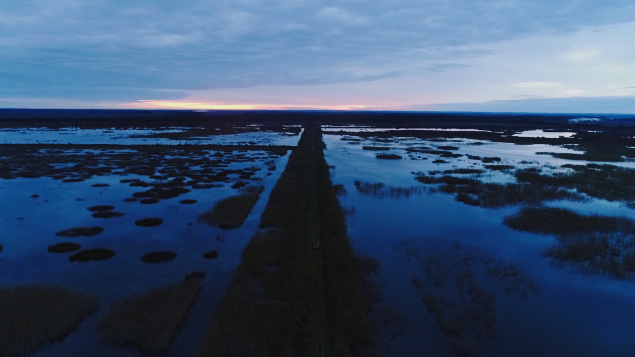 Evening light paints wetlands in calm blue tones with fading golden sky above
