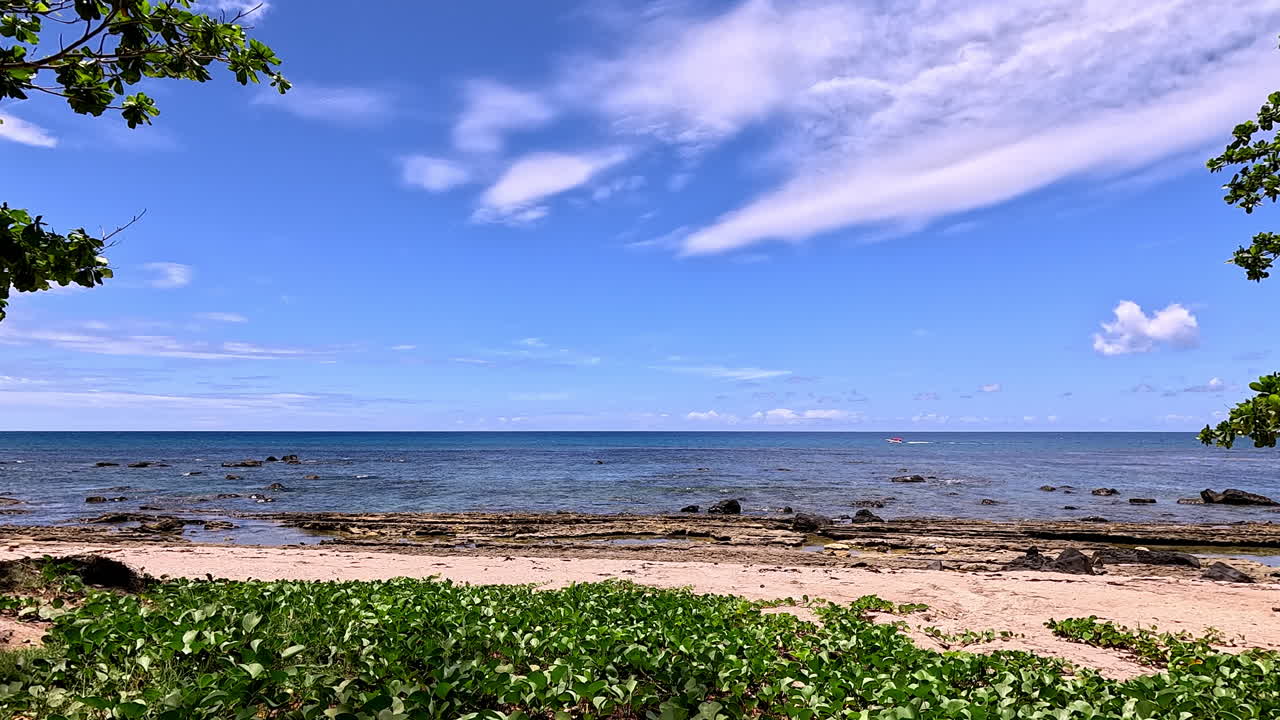 穏やかな青い水と砂浜の遠い水平線に沿って進むボート。