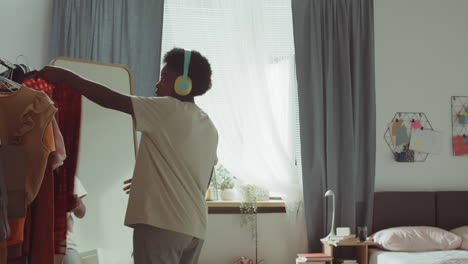 african american woman dancing and choosing clothes in bedroom