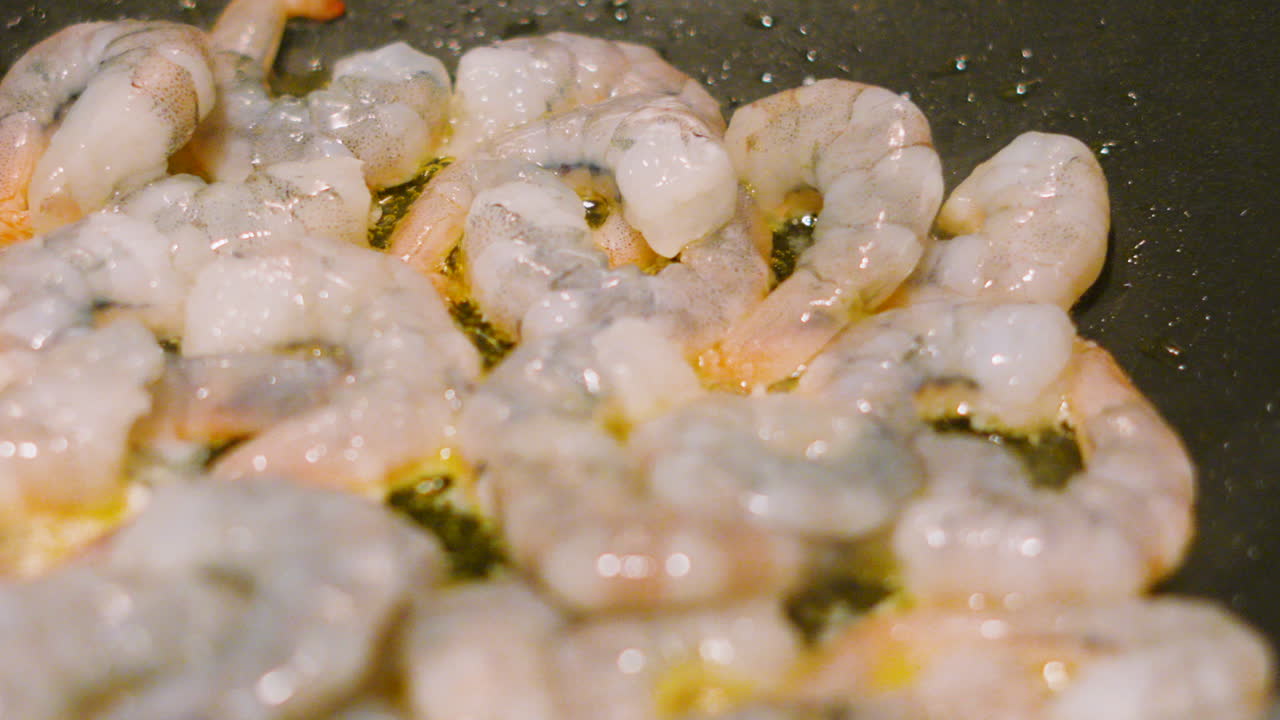 Slow Pan Across Large Raw Fresh King Prawns Cooking in Hot Frying Pan in Bubbling Olive Oil in Slow Motion. How to Cook Tasty Seafood Demonstration