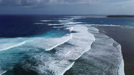 low aerial view of waves in the deep blue ocean with an island in the background in siargao, philippines