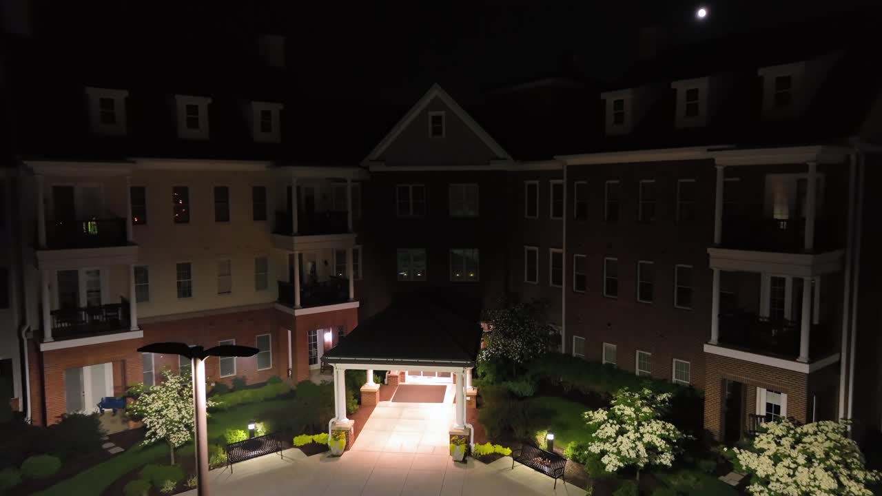 Aerial approaching shot of american apartment buildings with lighting entrance. Night scene and lighting Lantern in american suburb. Full moon at sky.