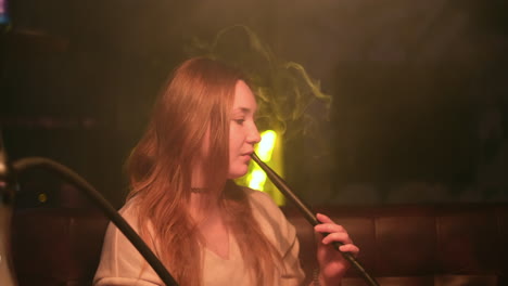 mujer fumando narguile en un club nocturno