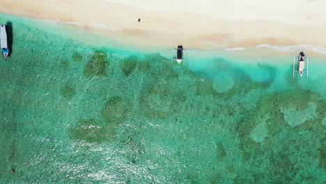 tourist boats docked by the beautiful white sand beach of the bahamas waiting on a sunny day - aerial shot