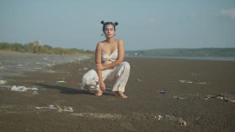 Mujer-Joven-De-Generación-Z-Segura-De-Sí-Misma,-Pose,-Cabello-Anudado,-Cara-Seria-Y-Atractiva,-Atuendo-Blanco,-Pantalones-Acampanados,-Top-Corto,-Aretes