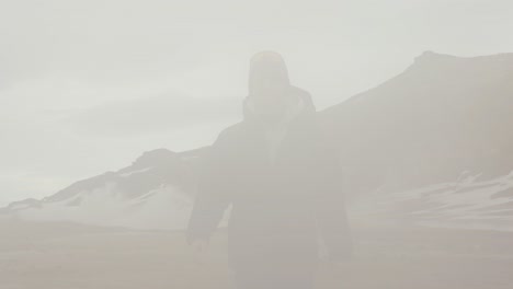 male fearlessly walk through dense vapor cloud from icelandic steam vent