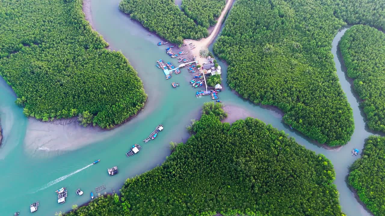 Aerial high angle overview of Phang Nga Bay, as boats drive up to dock in emerald waters passing limestone islands in mangrove forest