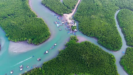 aerial high angle overview of phang nga bay, as boats drive up to dock in emerald waters passing limestone islands in mangrove forest