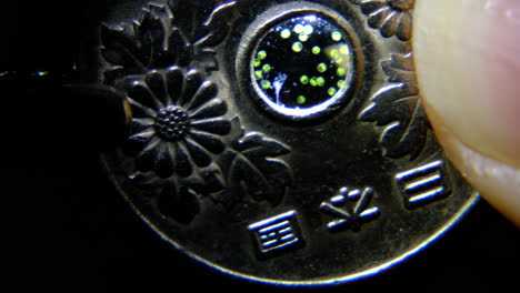 close-up of a japanese 5-yen coin with microorganisms in the hole
