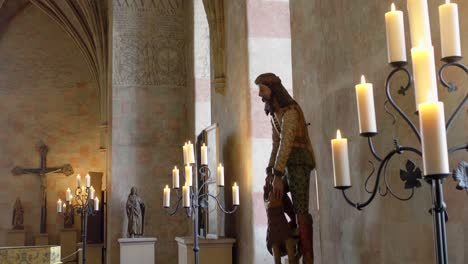 medieval church interior with statues and candlelight