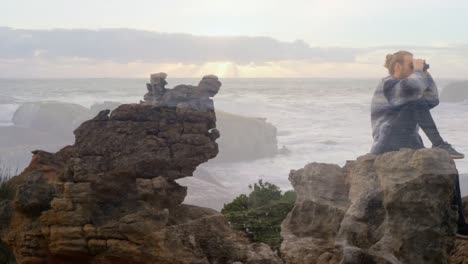 Animation-of-landscape-over-caucasian-man-sitting-on-rocks