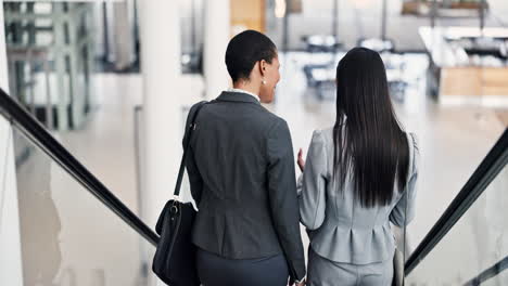 escalator, tablet and businesswomen in discussion