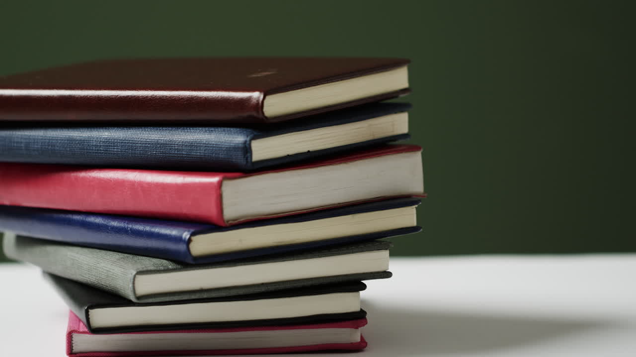 acercamiento de una pila de libros sobre un fondo verde, en cámara lenta