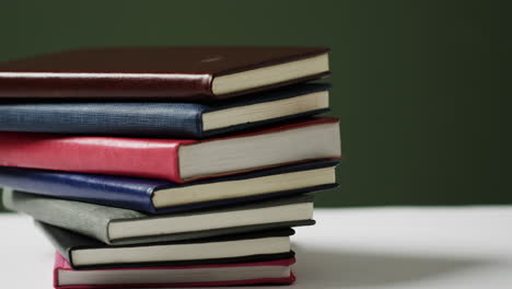 acercamiento de una pila de libros sobre un fondo verde, en cámara lenta