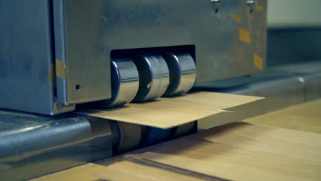 equipment at modern plant for doors manufacturing. shiny metal rollers letting out wooden veneer. close up.
