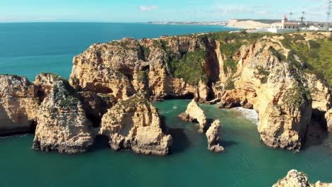 ponta da piedade lighthouse atop cliff in lagos, algarve, portugal - aerial eye level wide orbit shot