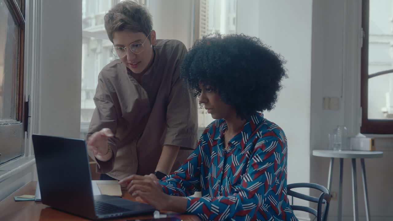 dos mujeres colaborando en una computadora portátil