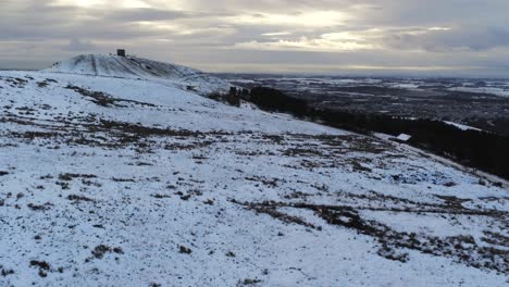 Snowy-Rivington-Pike-Tower-Winter-Hill-Vista-Aérea-Gente-Trineo-Cuesta-Abajo-Al-Amanecer-órbita-Derecha