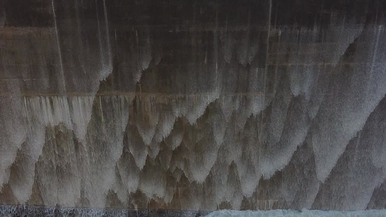 Close-up of water pouring over a dam wall as it overflows