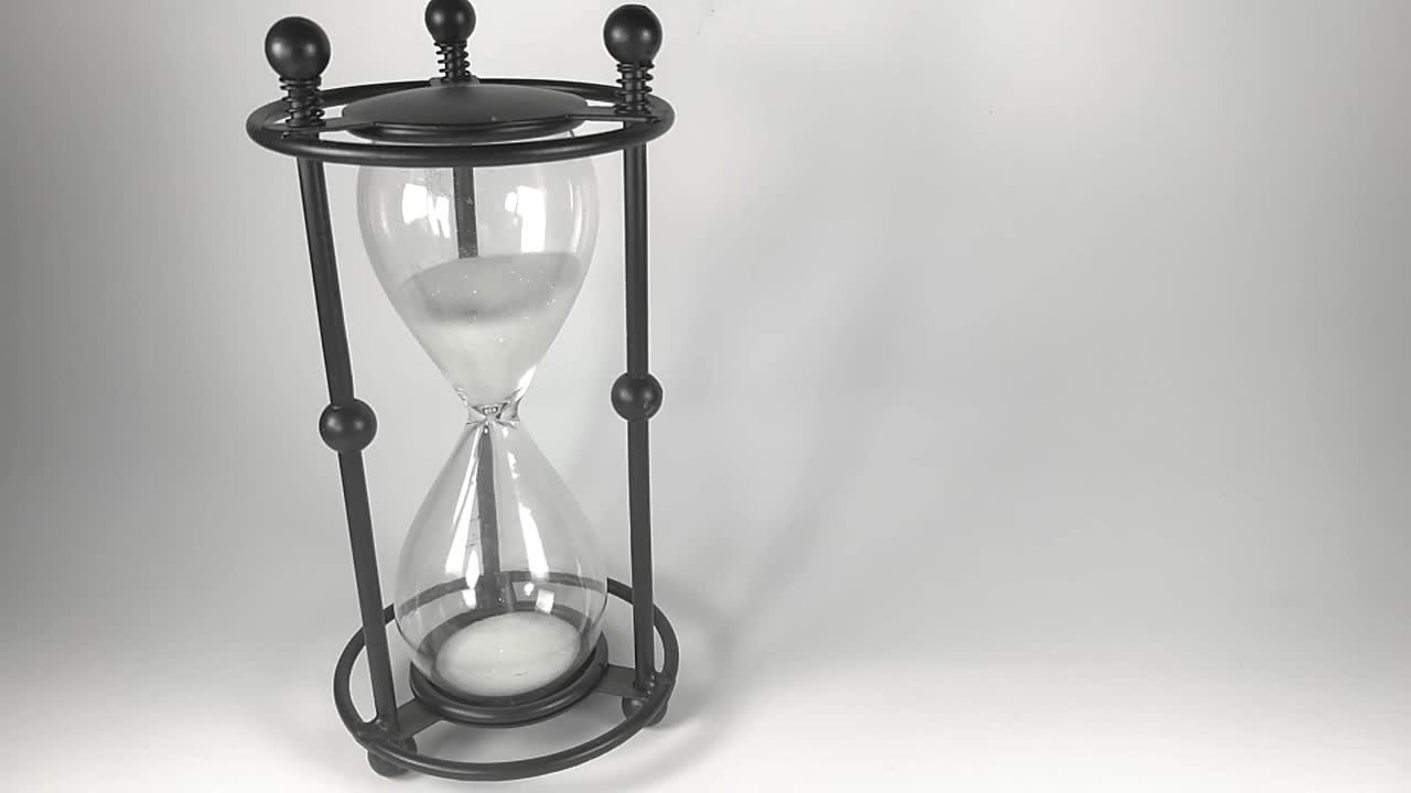 Black based hourglass with white sands of time falling to the bottom part, ISOLATED, STILL, TIMELAPSE