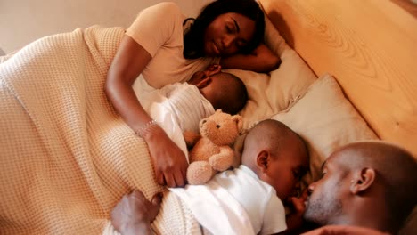 family with two sons sleeping together in bed