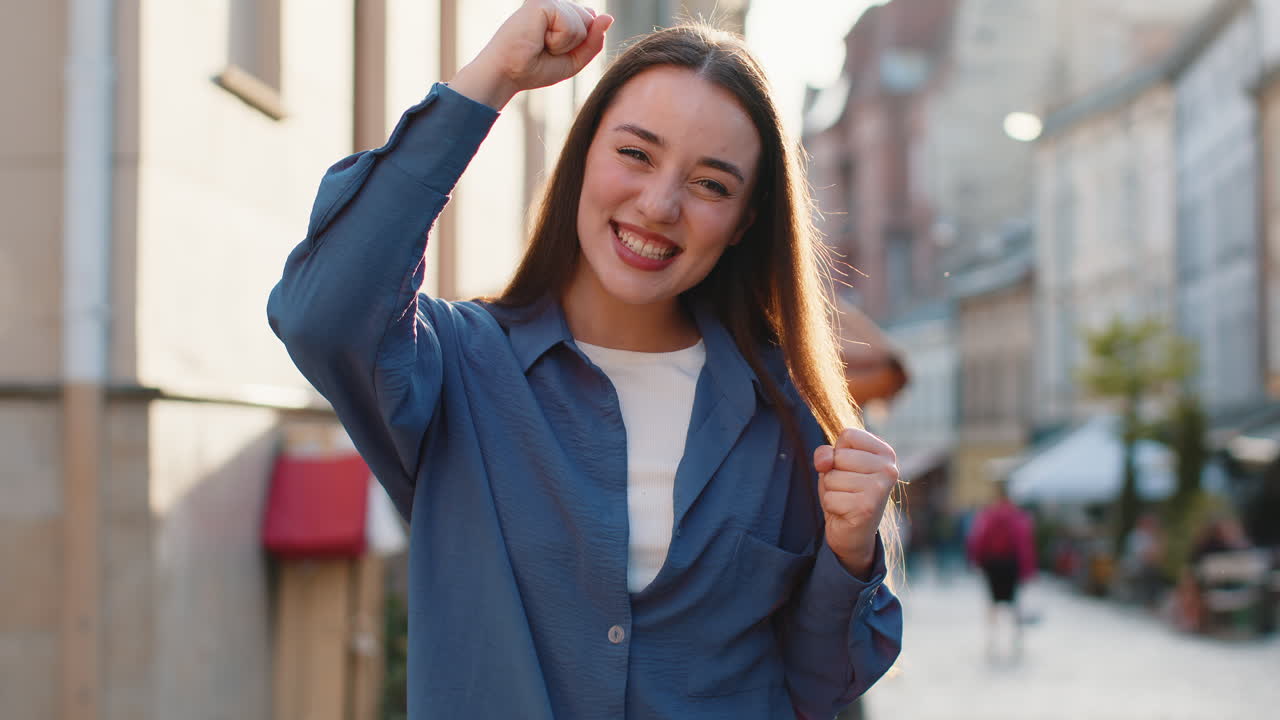 Young woman shouting celebrating success winning goal achievement good victory news in city street