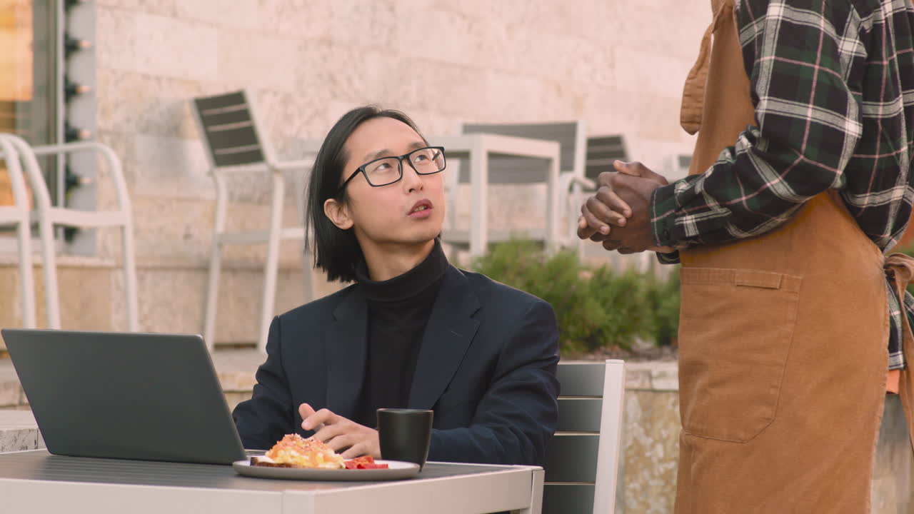 hombre de negocios que trabaja en una computadora portátil en una cafetería mientras un camarero le sirve comida